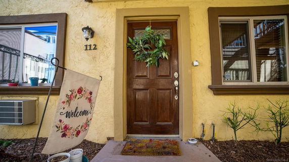 Front view of a house with a wooden door, welcome sign, and window.