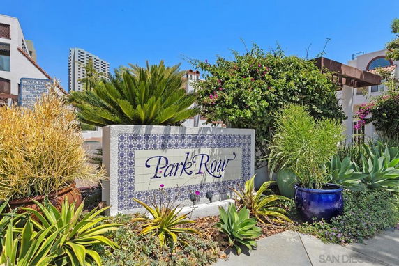 Front view of a residential area entrance with a decorative sign and potted plants.
