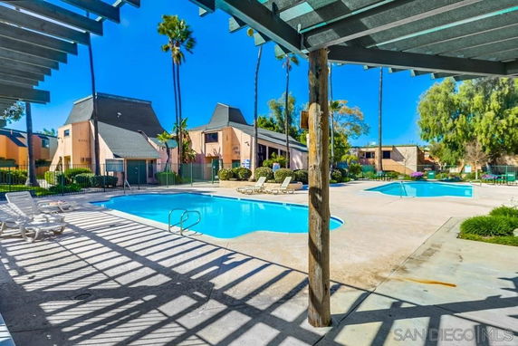 Outdoor swimming pool area with pergola and sun loungers in a residential complex.