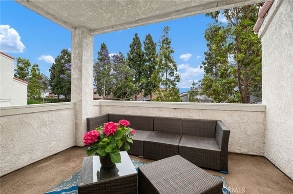 Outdoor seating area on a balcony with surrounding trees.