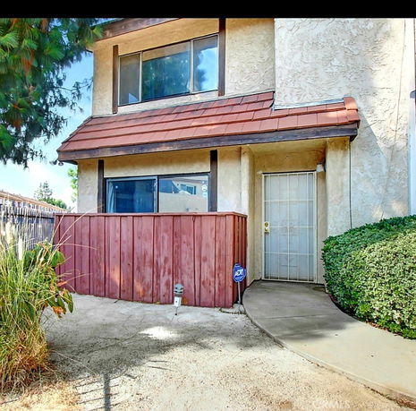 Front view of a two-story house with a small red wooden fence and a security door.