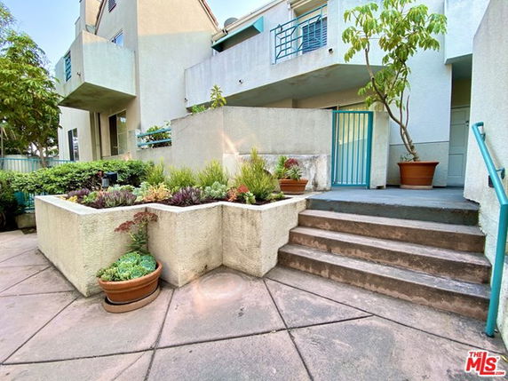 Front view of a multi-story building with stairs and potted plants.