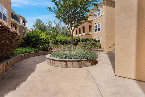 Front view of a two-story building with beige exterior and landscaped garden area.