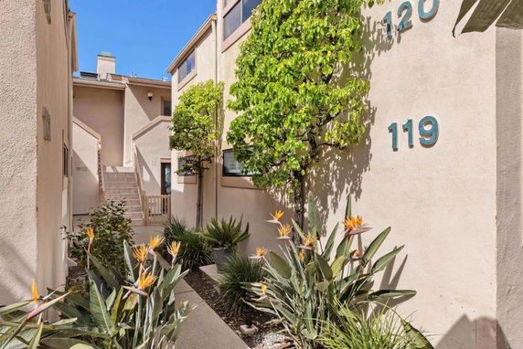 Front view of a residential building with stairs and plants.