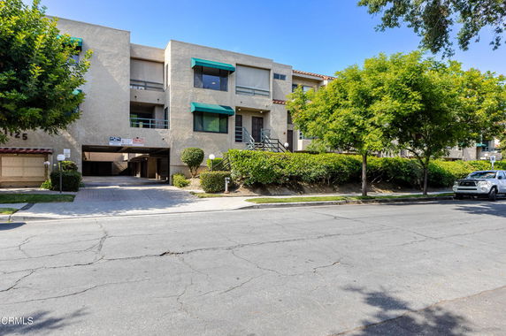 Front view of a multi-story apartment building with balconies and green awnings.