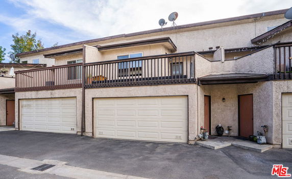 Front view of a townhouse with a double garage and a balcony above.
