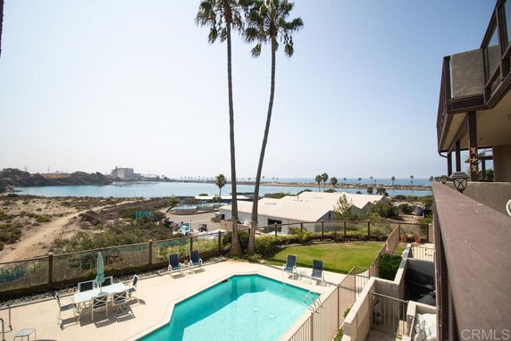 View of surrounding areas with a swimming pool and ocean in the background.