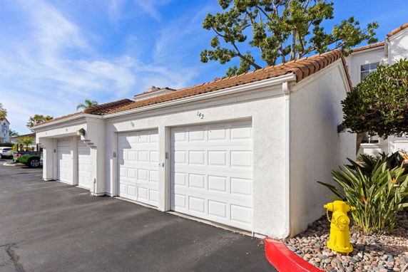 Front view of a building with a series of white garage doors and a tiled roof.