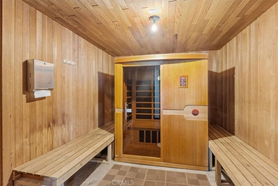 Interior view of a sauna room with wooden benches and a glass door.