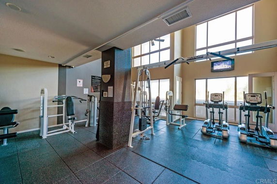 Interior view of a gym with exercise equipment and large windows.
