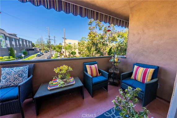 Balcony with outdoor seating overlooking street and buildings.