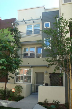Front view of a three-story townhouse with a modern design and small balcony.