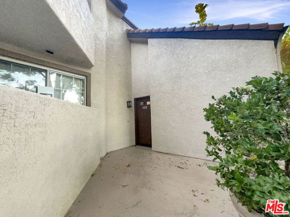 Entrance view of a house with a stucco exterior and brown door.
