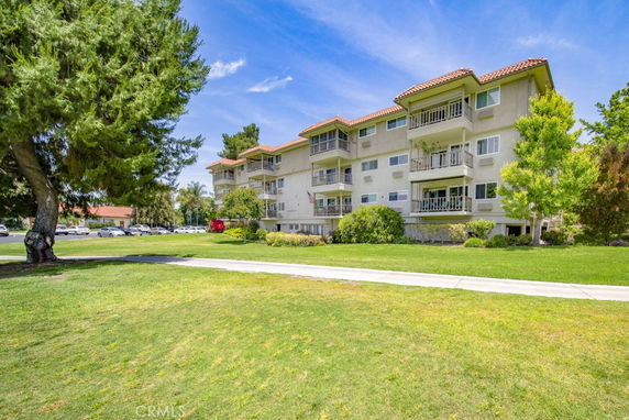 Front view of a multi-story residential building with balconies and a tile roof.