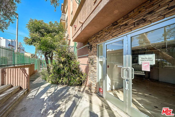 Front view of a building entrance with glass doors and stone wall accents.