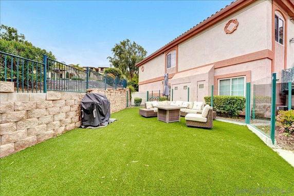 Side view of a building with a grass-covered outdoor area and patio furniture.