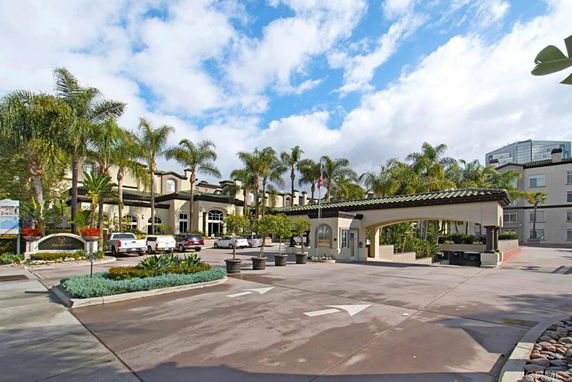 Front view of a large building with a grand entrance and palm trees.