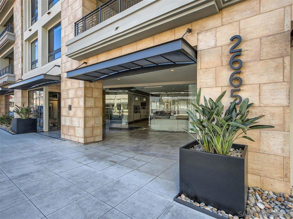 Front view of a modern building entrance with glass doors and large planters.