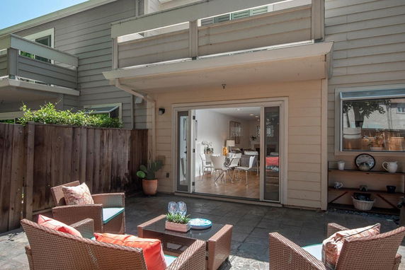 Exterior view of a two-story house with a patio and sliding glass doors.
