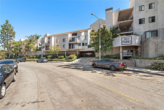 Front view of a multi-story residential building with parking area.