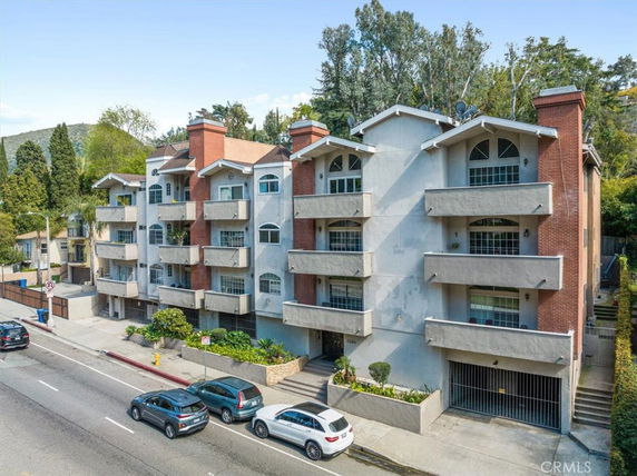 Front view of a multi-story apartment building with balconies and brick accents.
