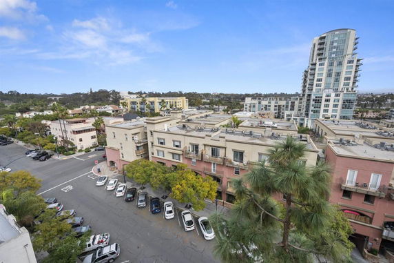 Aerial view of a multi-story apartment building with nearby residential and commercial structures.
