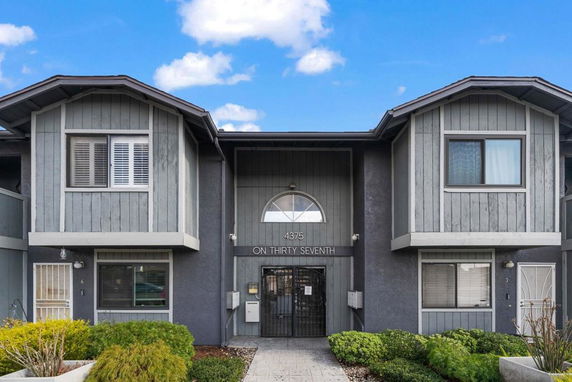 Front view of a multi-story residential building with a central entrance and two identical sections on each side.