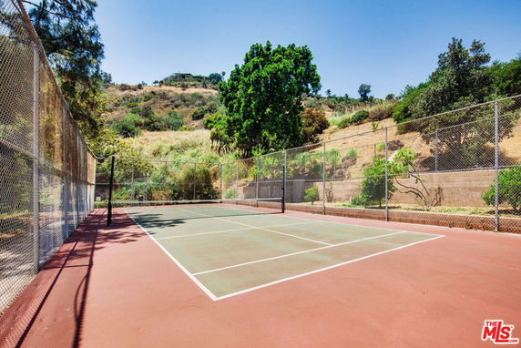 Open tennis court with surrounding hills and trees