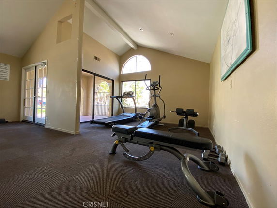 Interior view of a room with fitness equipment including treadmills and weight benches.