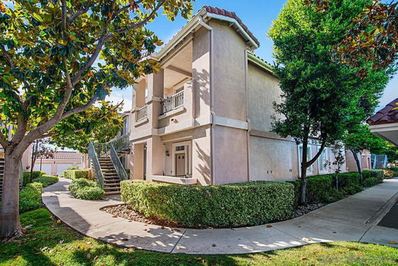 Front view of a two-story residential building with external staircases and a covered entrance.