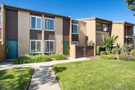 Front view of a two-story apartment complex with multiple windows and green doors.