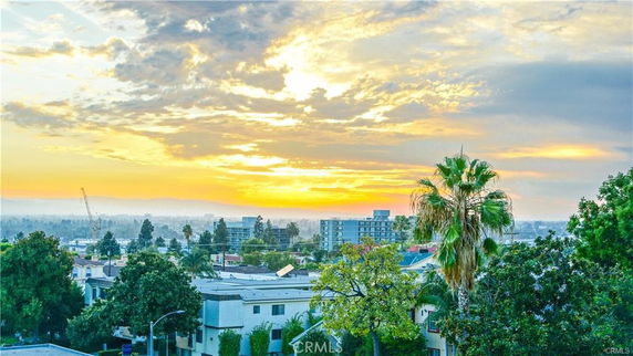 Panoramic view of a cityscape during sunset with buildings and trees.