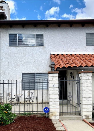 Front view of a two-story house with a tiled roof and gated entrance.