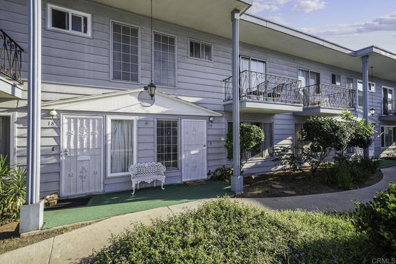 Front view of a two-story apartment building with balconies and decorative doors.