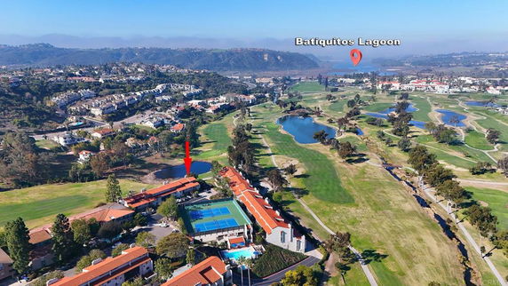 Panoramic view of a golf course with surrounding residential areas and a lagoon.