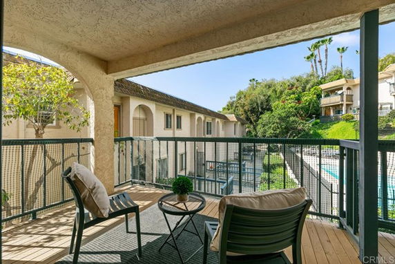 View from a balcony overlooking residential buildings and a swimming pool.