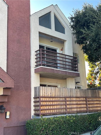 Front view of a multi-story house with balconies and wooden railing.