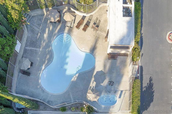 Aerial view of an outdoor swimming pool area with surrounding lounge chairs and umbrellas.