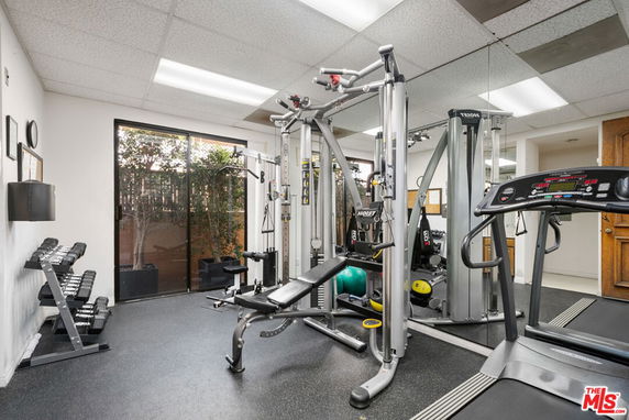 Indoor gym area with exercise equipment and mirrored walls.