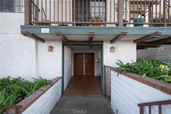 Front view of a multi-story residential building entrance with a balcony above.