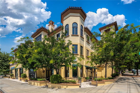 Front view of a multi-story commercial building with decorative window arches and a small entrance plaza.