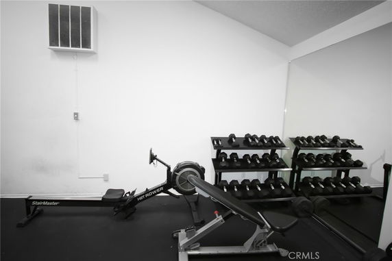 Indoor gym area with exercise equipment including a rowing machine and dumbbells.