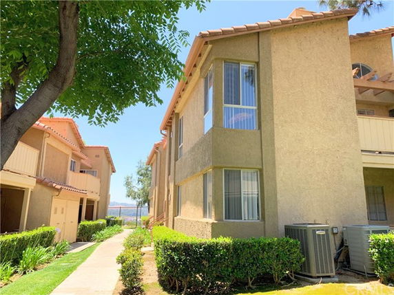 Front view of a multi-story residential building with beige exterior and large windows.