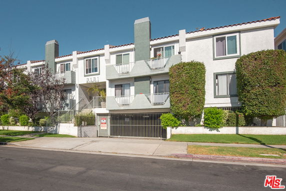 Front view of a multi-story apartment building with balconies and a gated entrance.