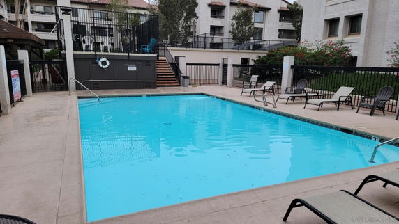 Outdoor swimming pool area with surrounding fence and seating.