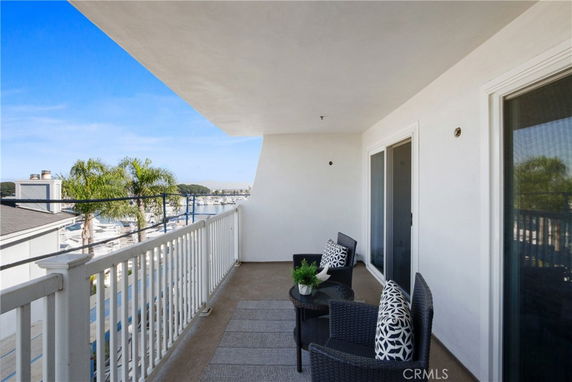 Outdoor balcony with seating overlooking marina and palm trees