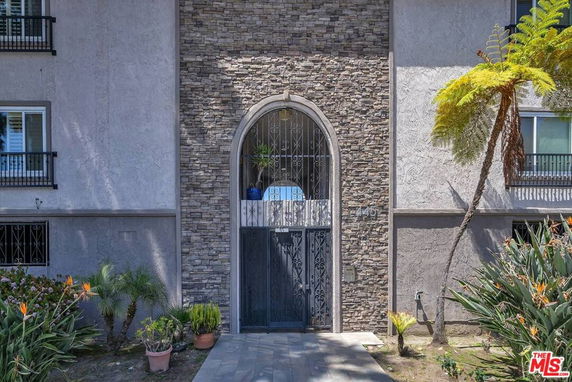 Front view of a building entrance with a stone archway and metal gate.