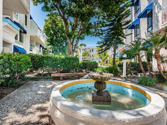 Outdoor area with a water fountain and surrounding residential buildings.