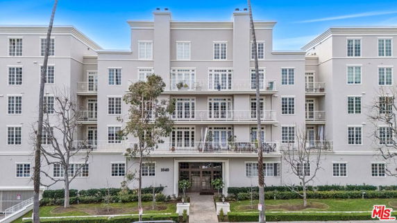 Front view of a multi-story residential building with balconies and large windows.
