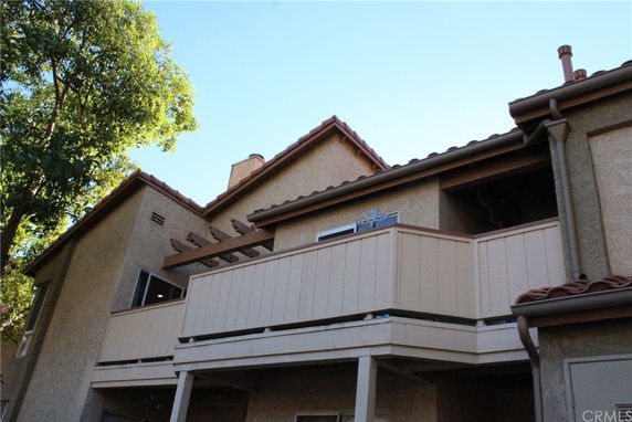 Front view of a multi-story residential building with balconies and red-tiled roof.
